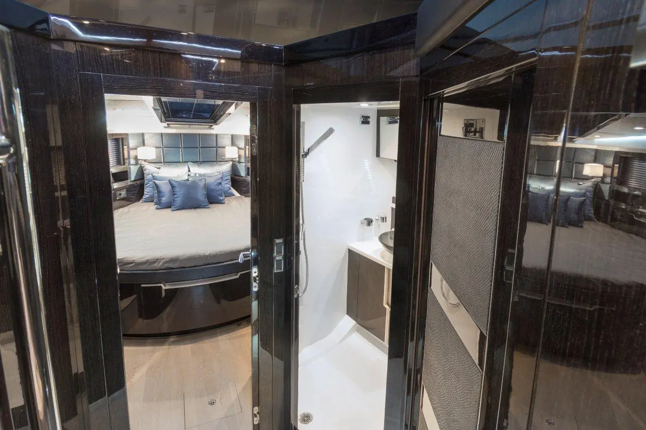 Luxurious yacht interior featuring a bedroom with a round bed and en-suite bathroom with modern fixtures and elegant decor.