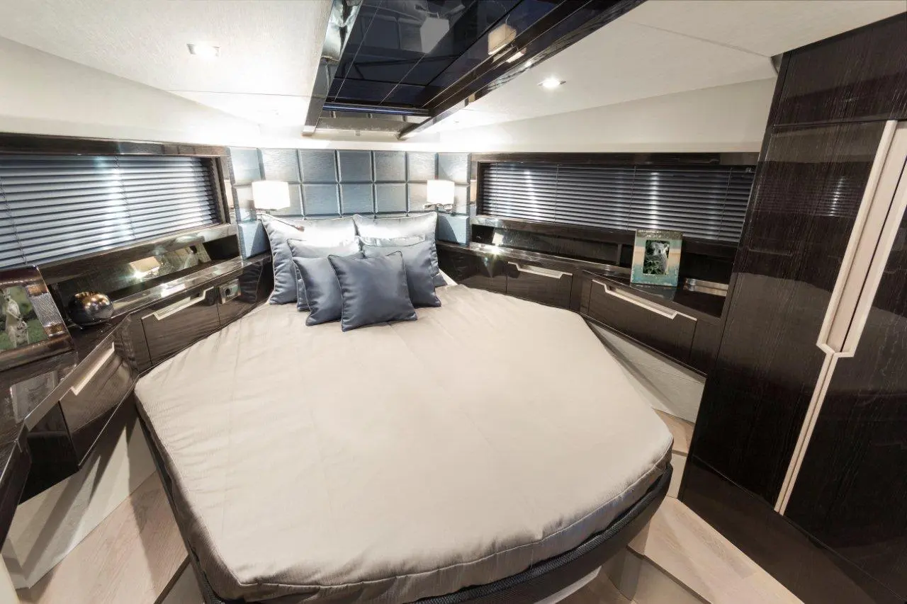 Luxurious yacht bedroom featuring a circular bed, blue satin pillows, modern cabinetry, and stylish lighting.