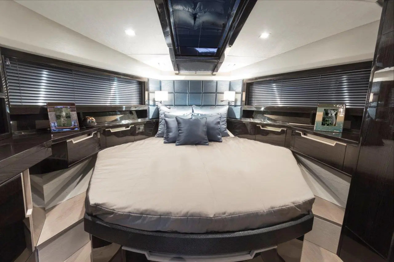 Luxury boat interior featuring a round bed with blue cushions, modern cabinetry, and a skylight above.