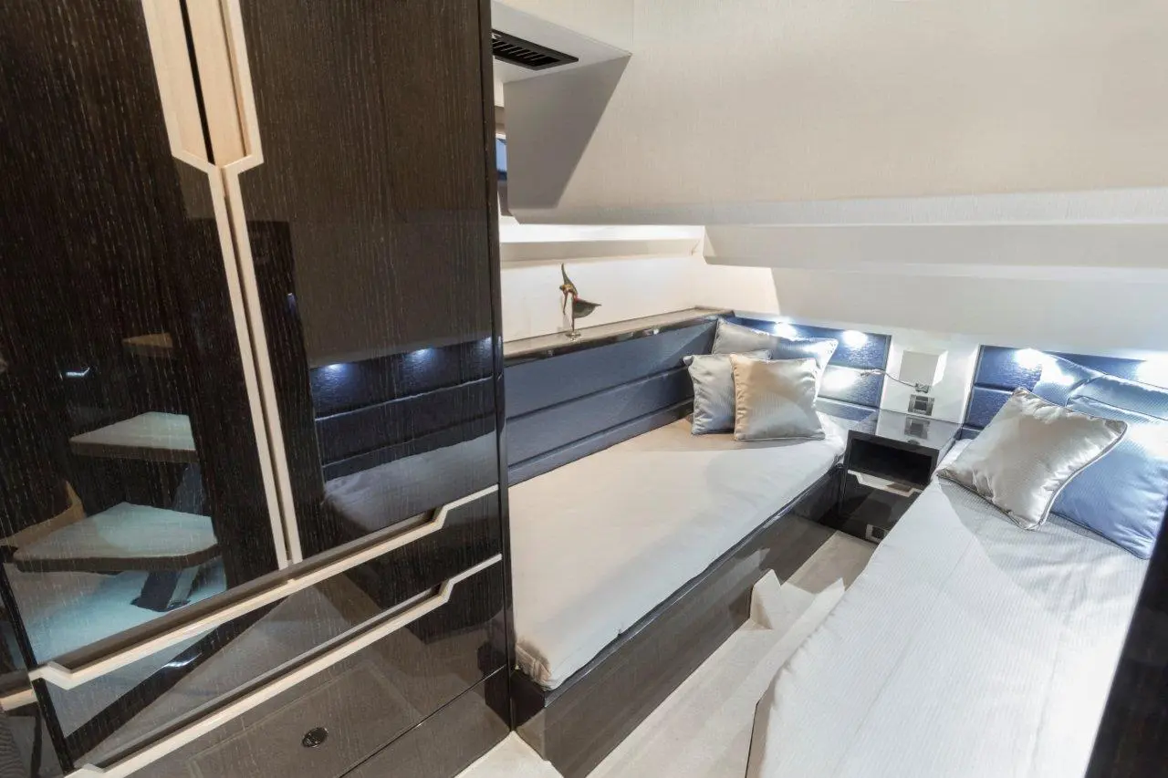 Stylish boat interior featuring twin beds with cushions, sleek cabinetry, and ambient lighting for a luxurious atmosphere.