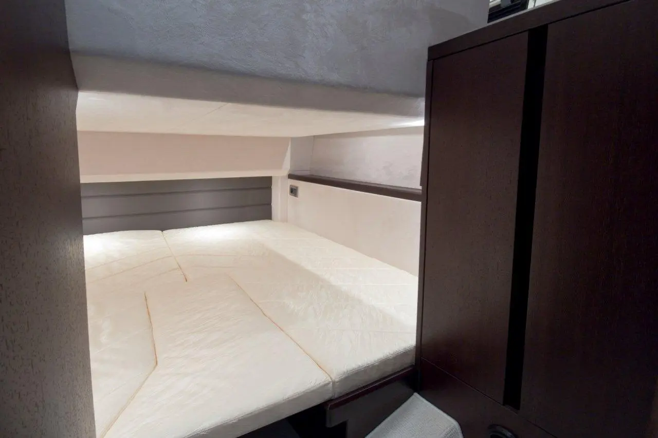 A modern bedroom featuring a large, white mattress, wooden cabinets, and soft overhead lighting for a cozy atmosphere.