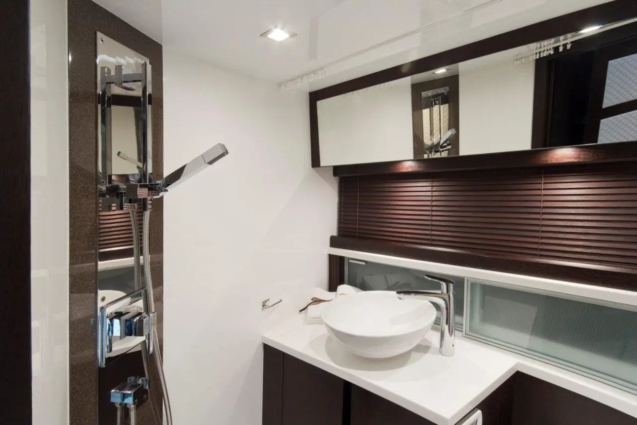 Sleek modern bathroom featuring a shower with controls, a round vessel sink, and stylish dark wood accents.