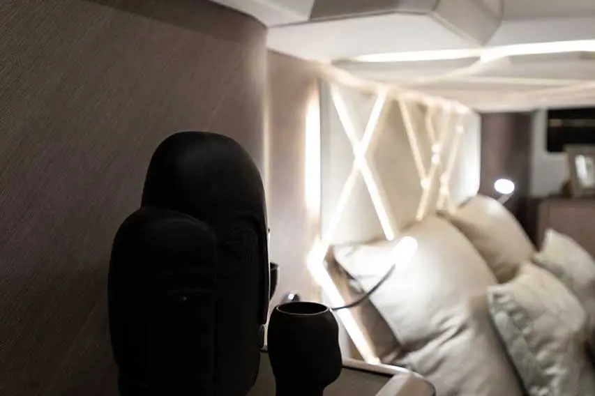 Decorative black sculptures and a dark cup near soft pillows against a modern, softly lit wall design in a cozy interior.