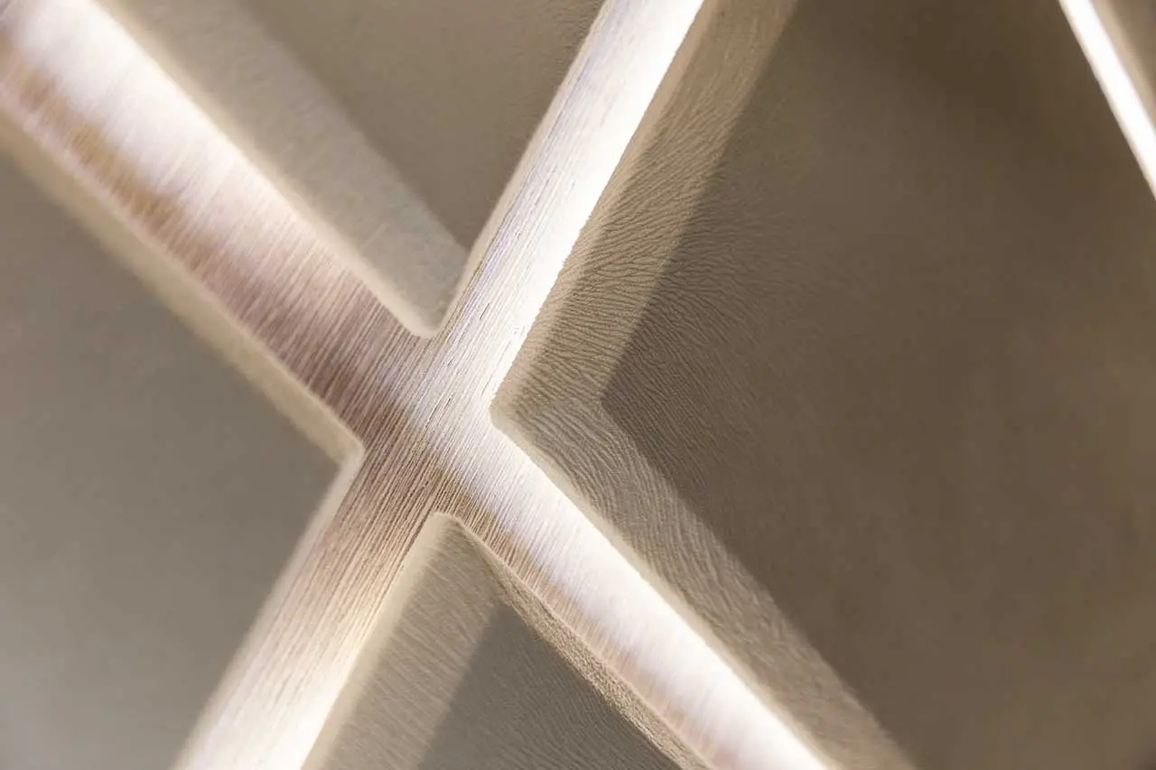 Close-up of a textured surface with a prominent geometric pattern forming an 'X' shape illuminated by soft lighting.