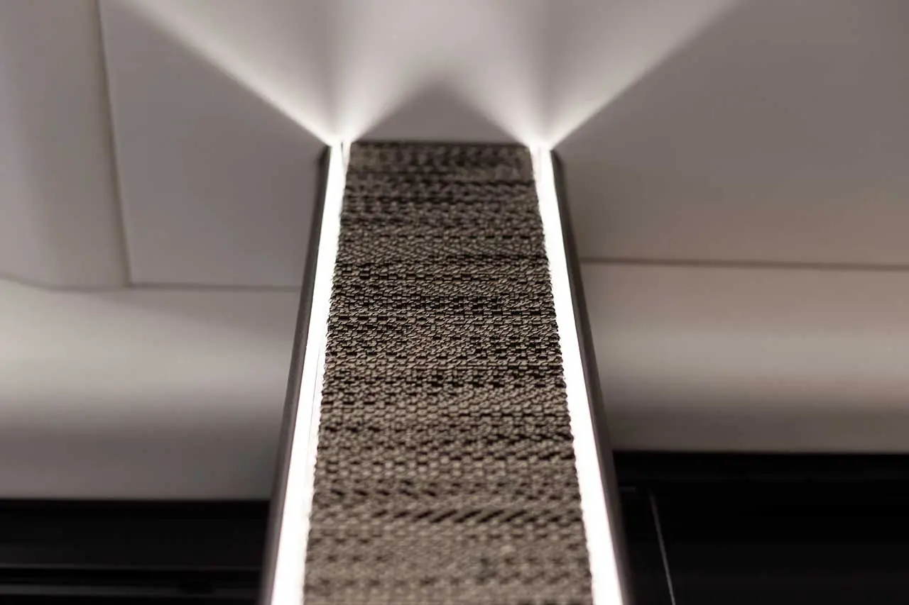 Modern ceiling light fixture with textured black panel, illuminated edges, and sleek white background.