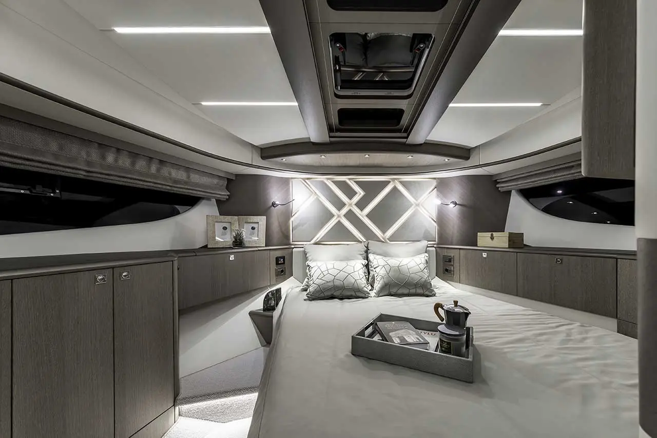 Modern yacht interior featuring a cozy bed, elegant lighting, and stylish decor with storage cabinets and a coffee tray.
