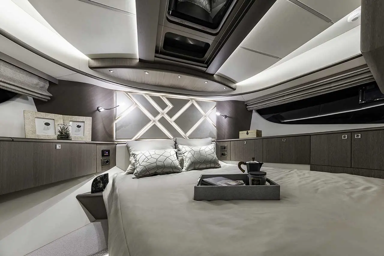 Modern yacht bedroom featuring a spacious bed with decorative pillows, ambient lighting, and stylish storage compartments.