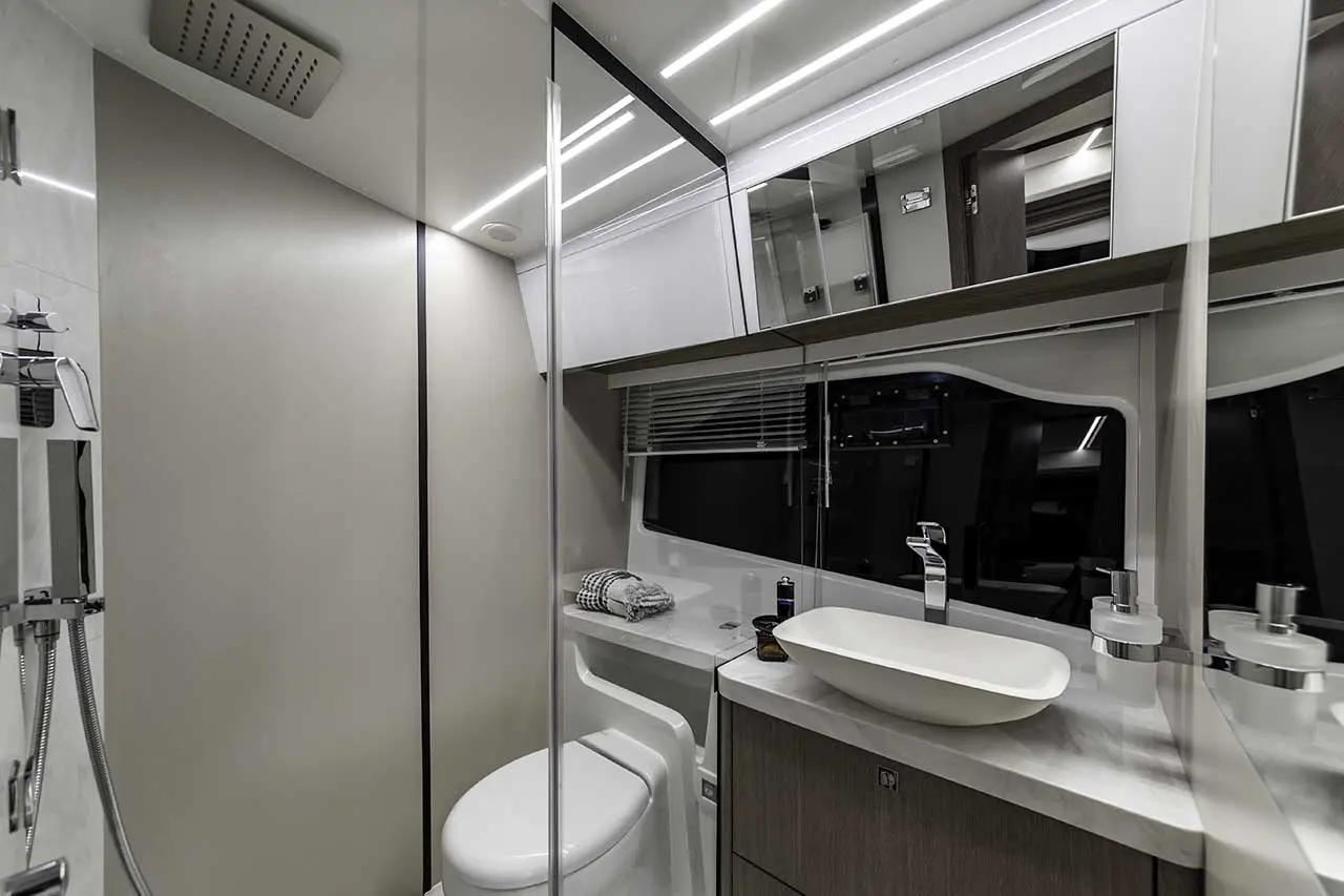 Modern bathroom featuring a stylish sink, toilet, mirrors, and ambient lighting with a towel on the countertop.