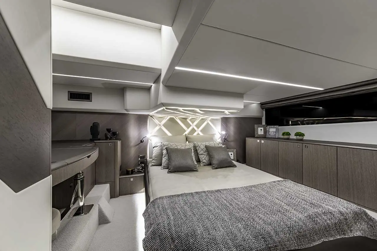 Modern yacht bedroom featuring a bed with decorative pillows, sleek cabinetry, and ambient lighting.