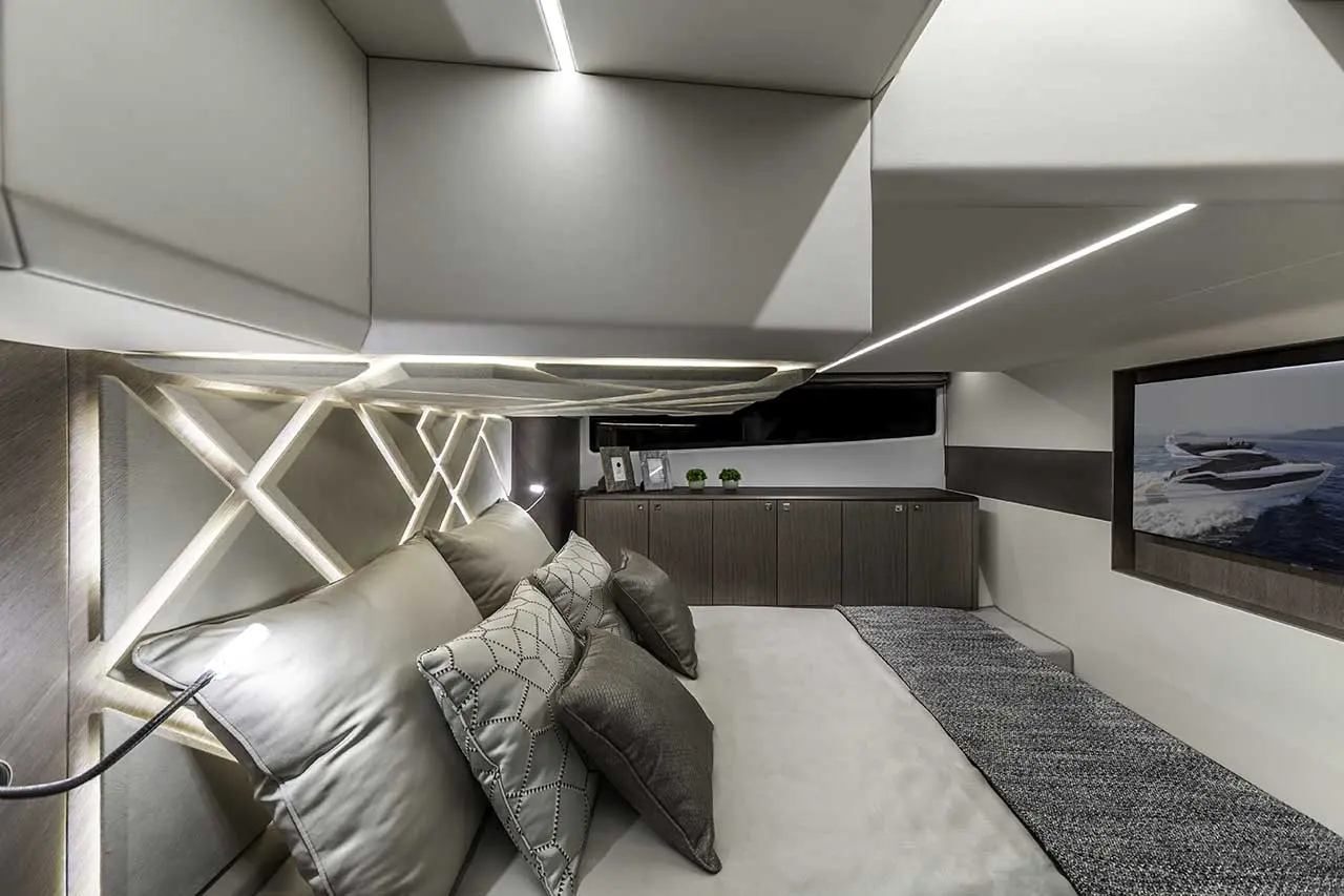 Modern boat interior featuring plush bedding, decorative lighting, wall art, and a sleek design with storage cabinets.