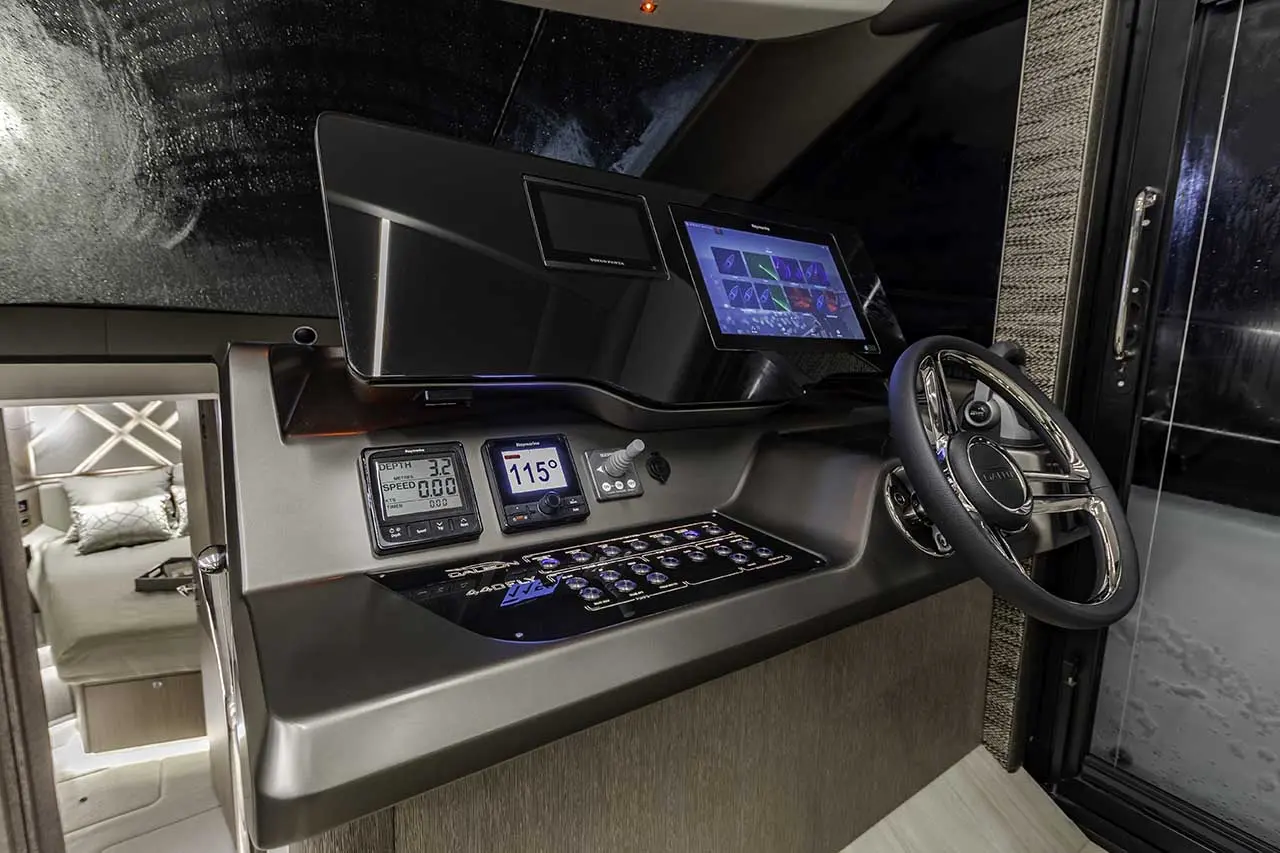 Modern boat dashboard displaying digital gauges for depth (3.2) and speed (0.00), with a touchscreen display and steering wheel.