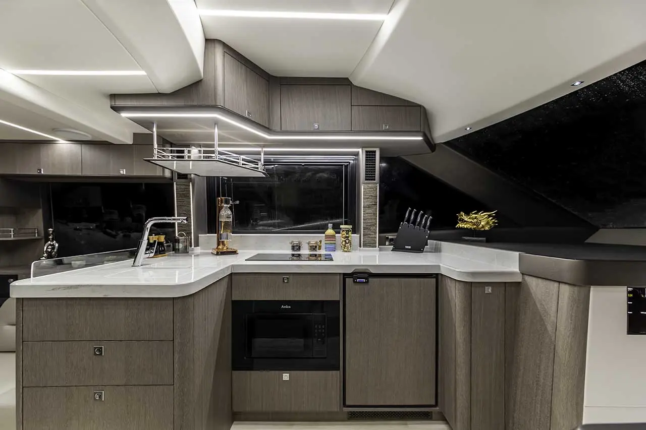 Modern yacht kitchen featuring grey cabinetry, a glass window, integrated microwave, and stylish decor elements.