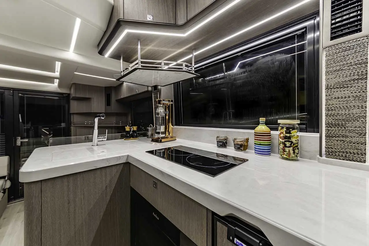 Modern kitchen featuring sleek cabinetry, marble countertop, induction hob, colourful storage jars, and stylish pendant lighting.