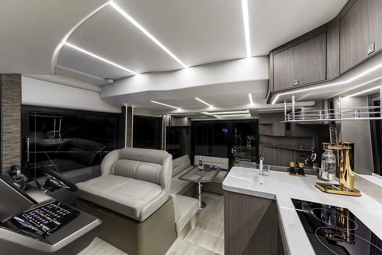 Modern motorhome interior with sleek design, featuring a driver's seat, kitchen area, and ambient LED lighting.
