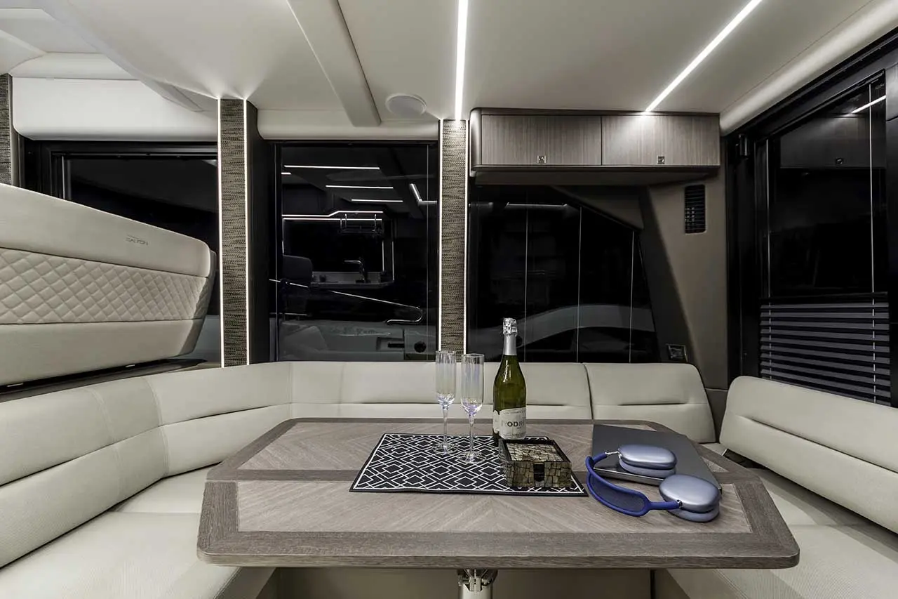 Luxurious yacht interior featuring a dining area with a wooden table, champagne, glasses, and elegant decor.