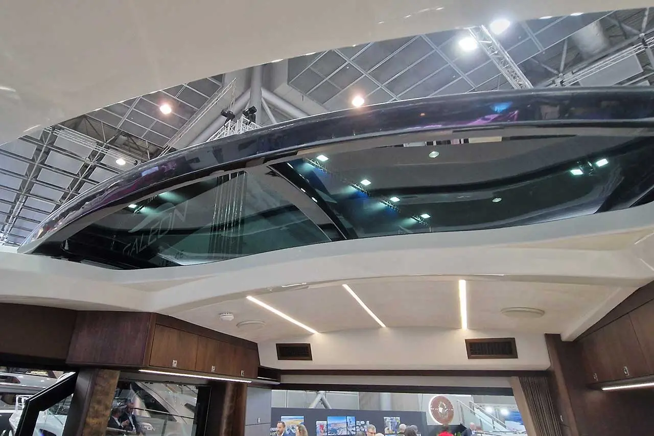 Interior view of a luxury yacht featuring a large glass skylight above a modern cabin with wooden accents and indirect lighting.