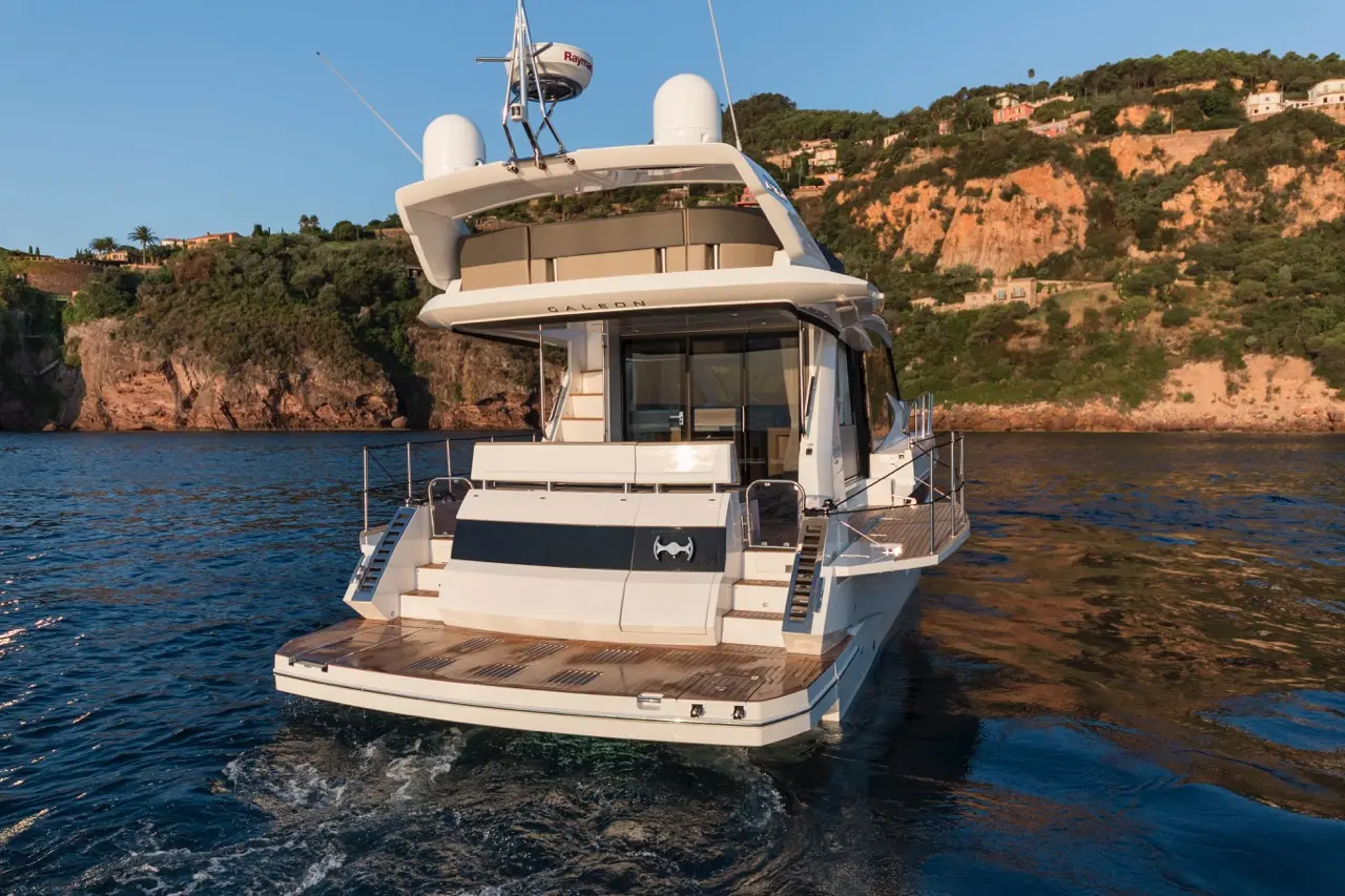Luxury Galeon yacht anchored near coastal cliffs and greenery, showcasing a sleek design and peaceful waters.