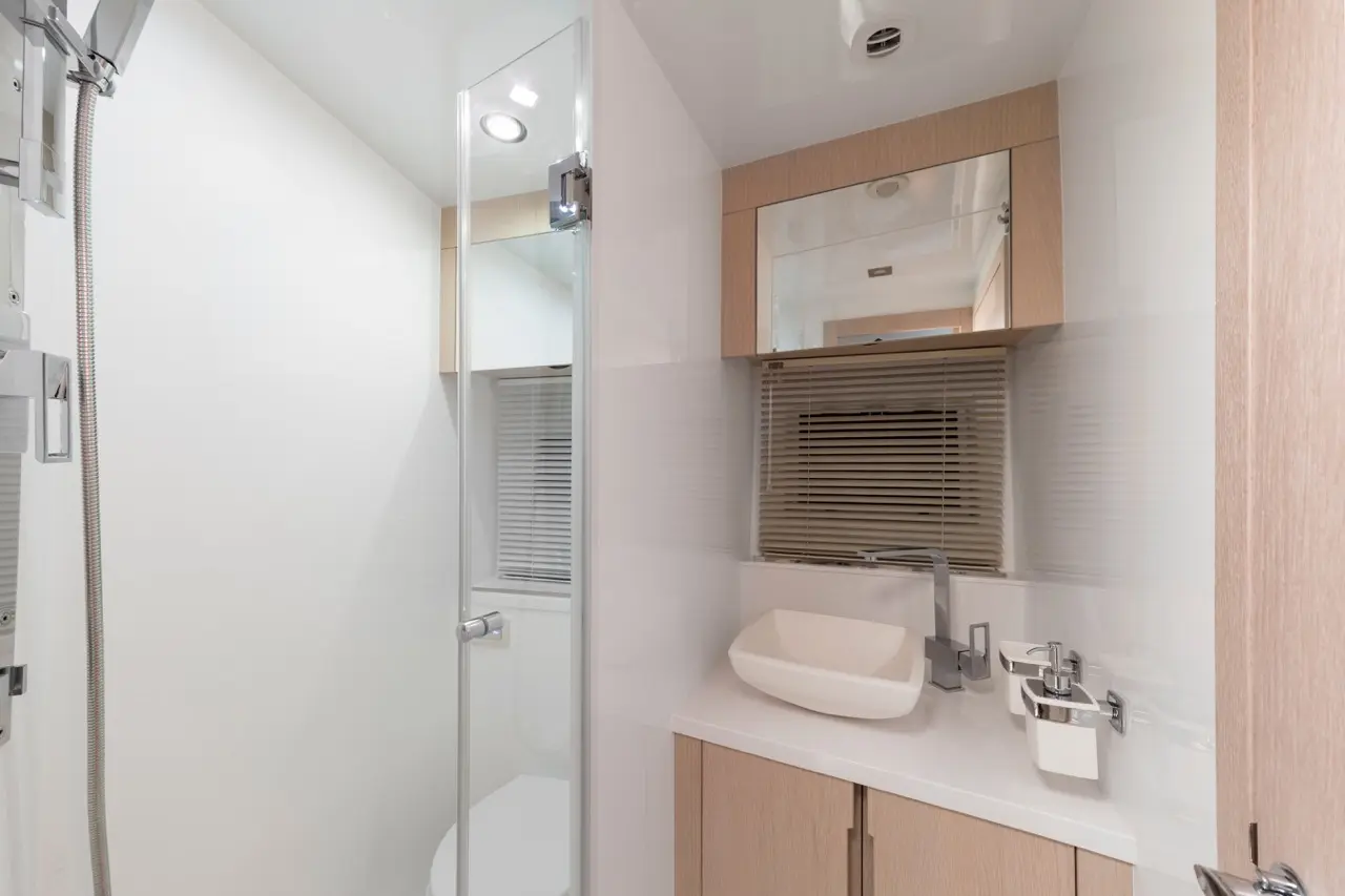 Modern bathroom featuring a glass shower, sleek sink, wooden cabinetry, and ambient lighting for a clean, minimalist look.
