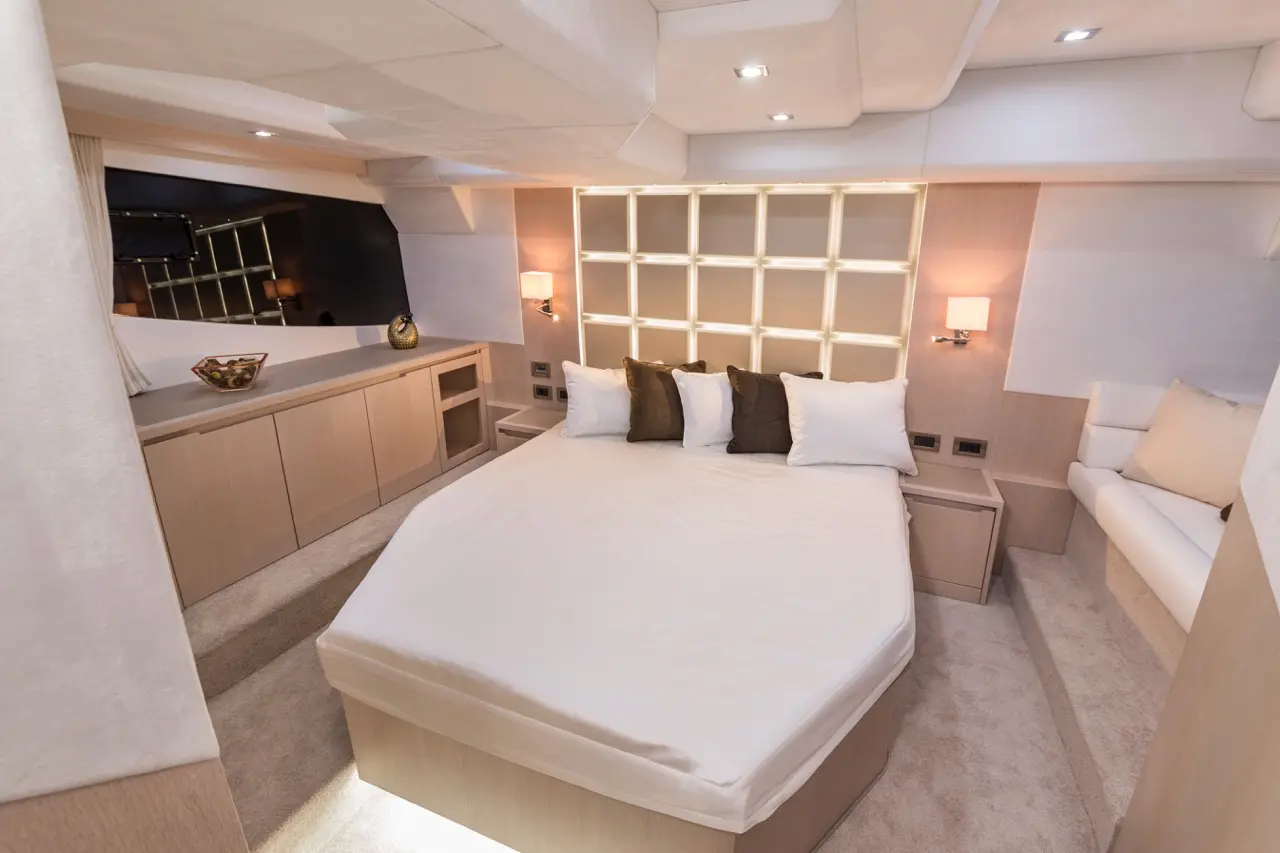 Modern yacht bedroom featuring a round bed with several pillows, elegant wooden accents, and stylish lighting.