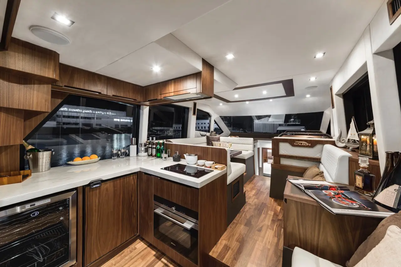 Luxurious yacht interior with a modern kitchen area, stylish seating, and a view of the marina at night.