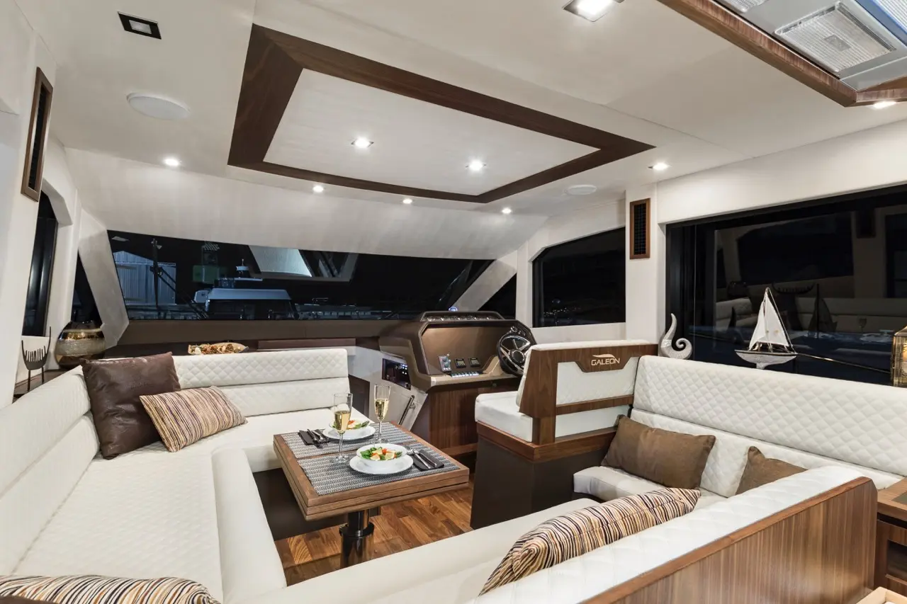 Luxurious boat interior featuring a seating area, table with food, and a stylish helm with a view of the water.