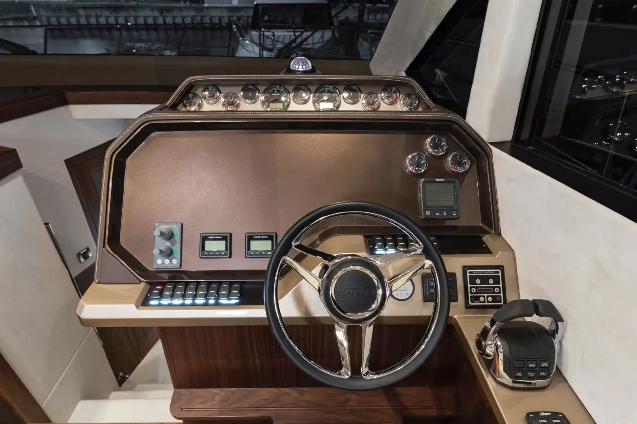 Boat dashboard featuring a steering wheel, gauges, control buttons, and a microphone, designed for navigation and communication.