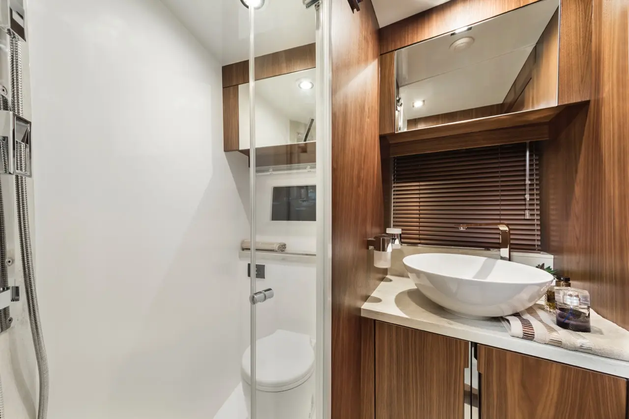 Modern bathroom featuring a walk-in shower, a white basin, wooden cabinets, and ambient lighting.