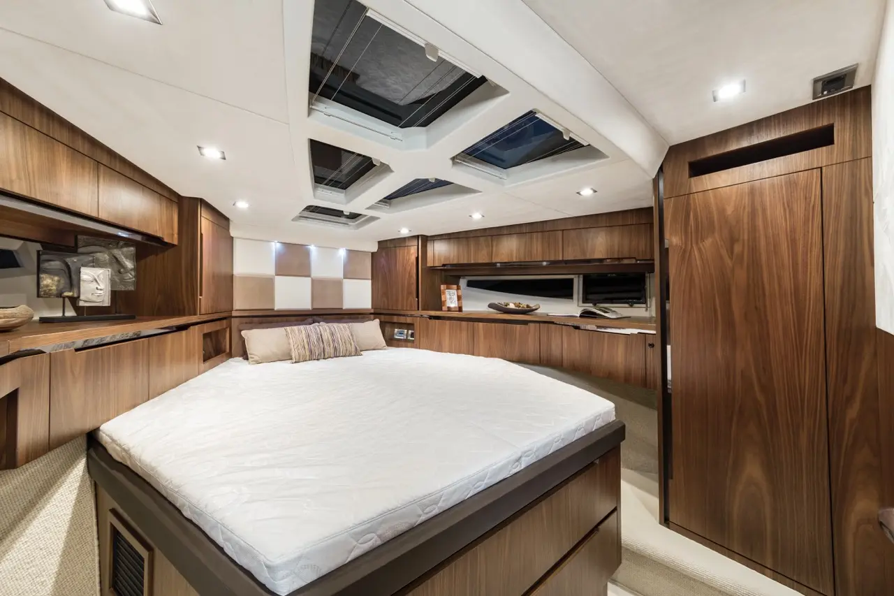 Elegant yacht bedroom featuring a large bed, wooden cabinetry, and multiple skylights for natural light.