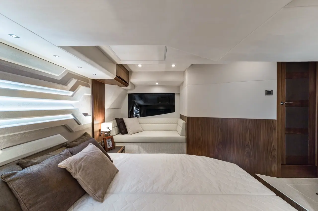 Luxury boat interior featuring a double bed, stylish sofa, and modern lighting. Warm wood finishes enhance elegance.