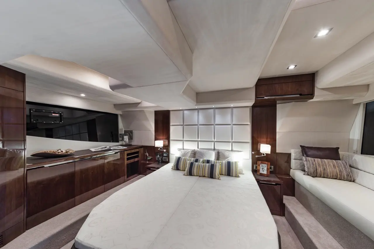 Modern yacht cabin featuring a double bed, stylish decor, wooden furniture, and ambient lighting for a luxurious atmosphere.