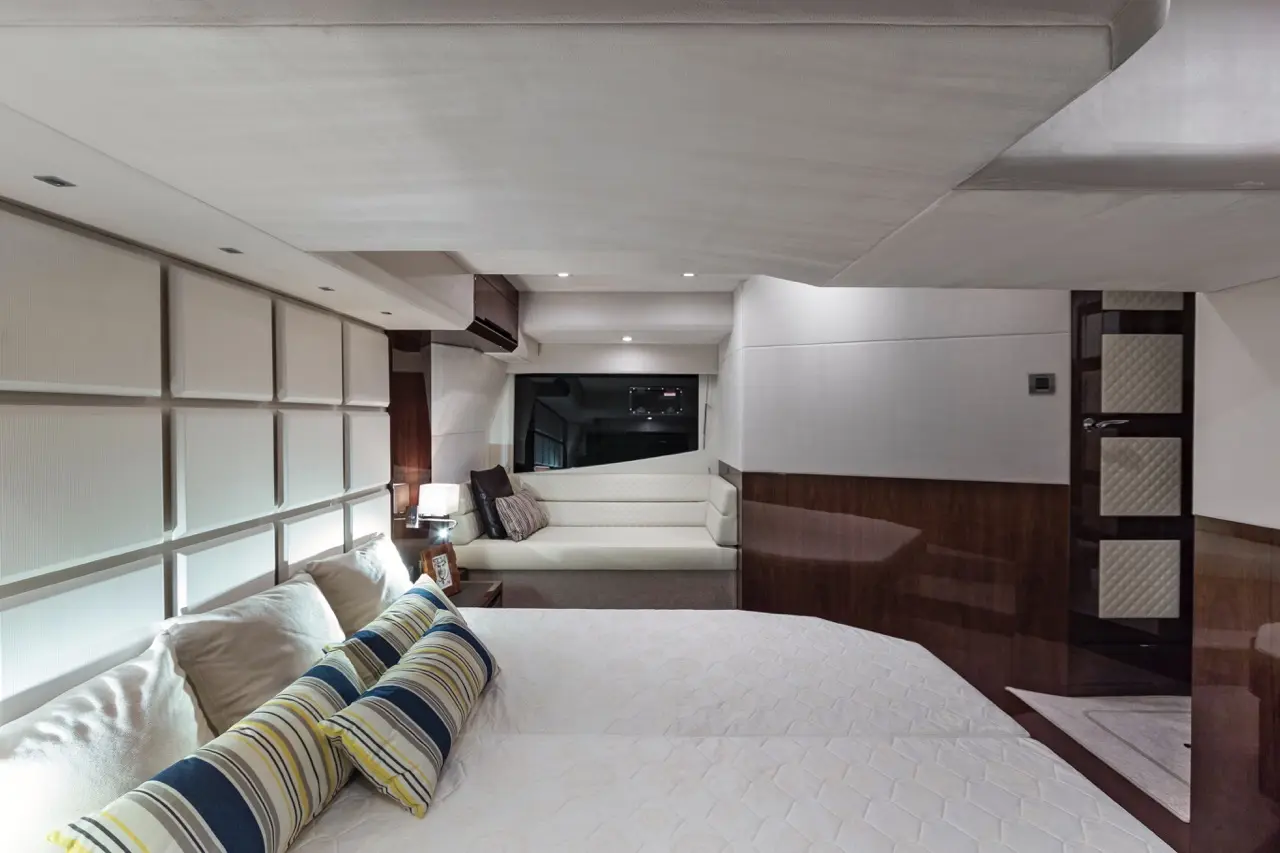 Luxurious yacht interior featuring twin beds with decorative pillows, a plush seating area, and soft ambient lighting.