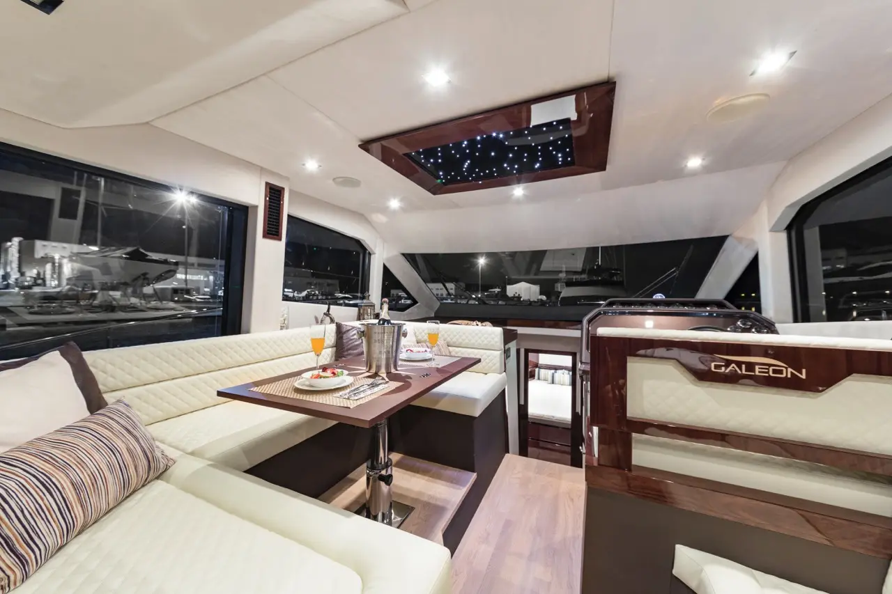 Luxurious yacht interior featuring cozy seating, a dining table with food, champagne, and a starry skylight by Galeon.