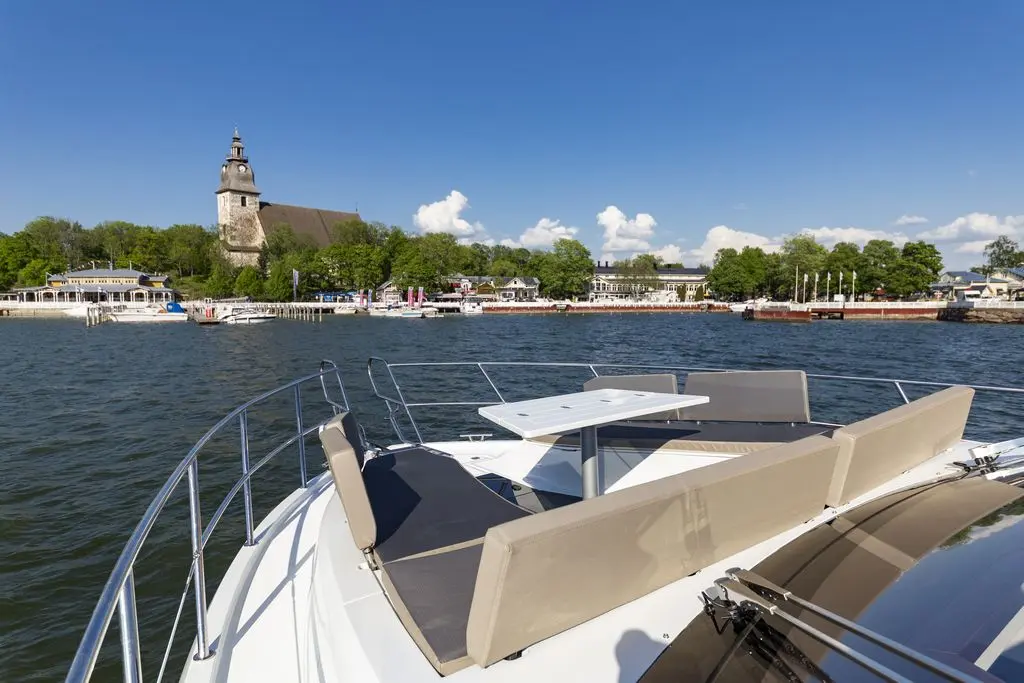 View from a boat showing a table and seating, with a church and waterfront buildings in the background under a clear blue sky.