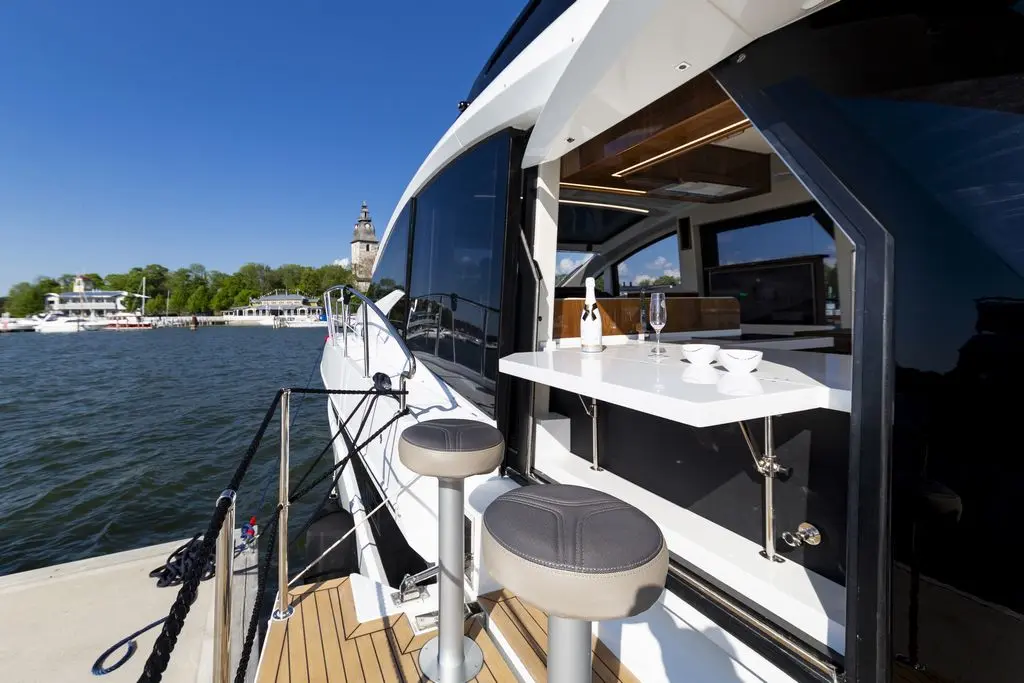 Luxury yacht with a view of the dock, featuring a stylish bar area, champagne bottle, and glass by the water.
