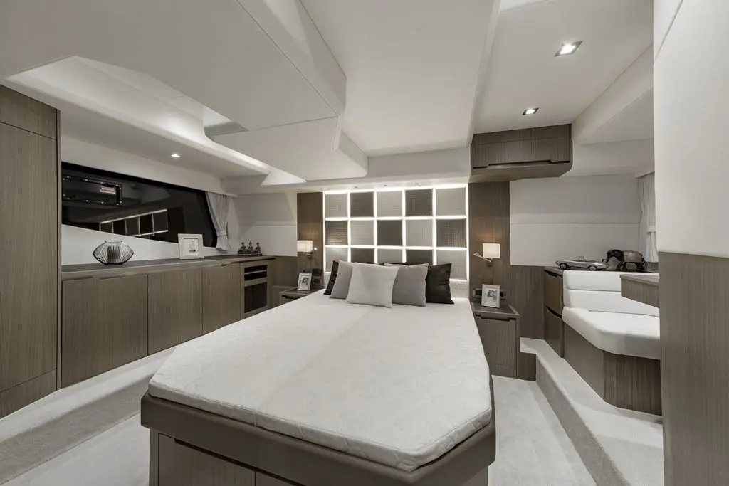 Modern yacht bedroom with a queen-size bed, stylish cabinetry, and soft lighting, featuring a cozy seating area and decor.