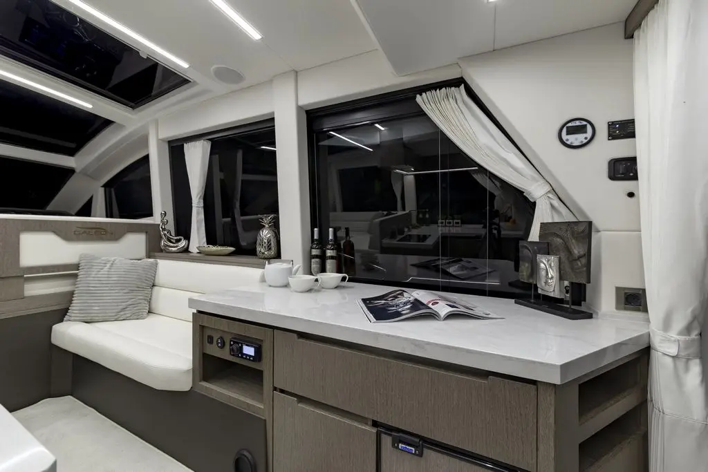 Modern yacht interior with a white and grey color scheme, featuring a plush seating area, marble countertop, and decorative items.