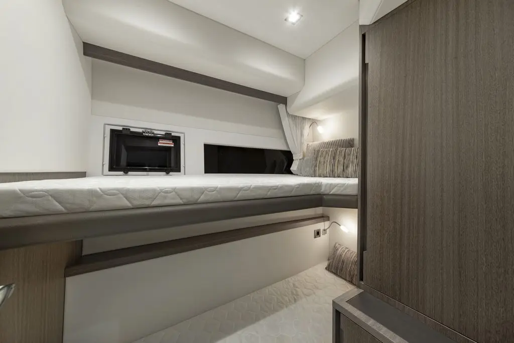 Compact modern bedroom with a wall-mounted TV, a double bed, and soft lighting, featuring wood and neutral colour tones.