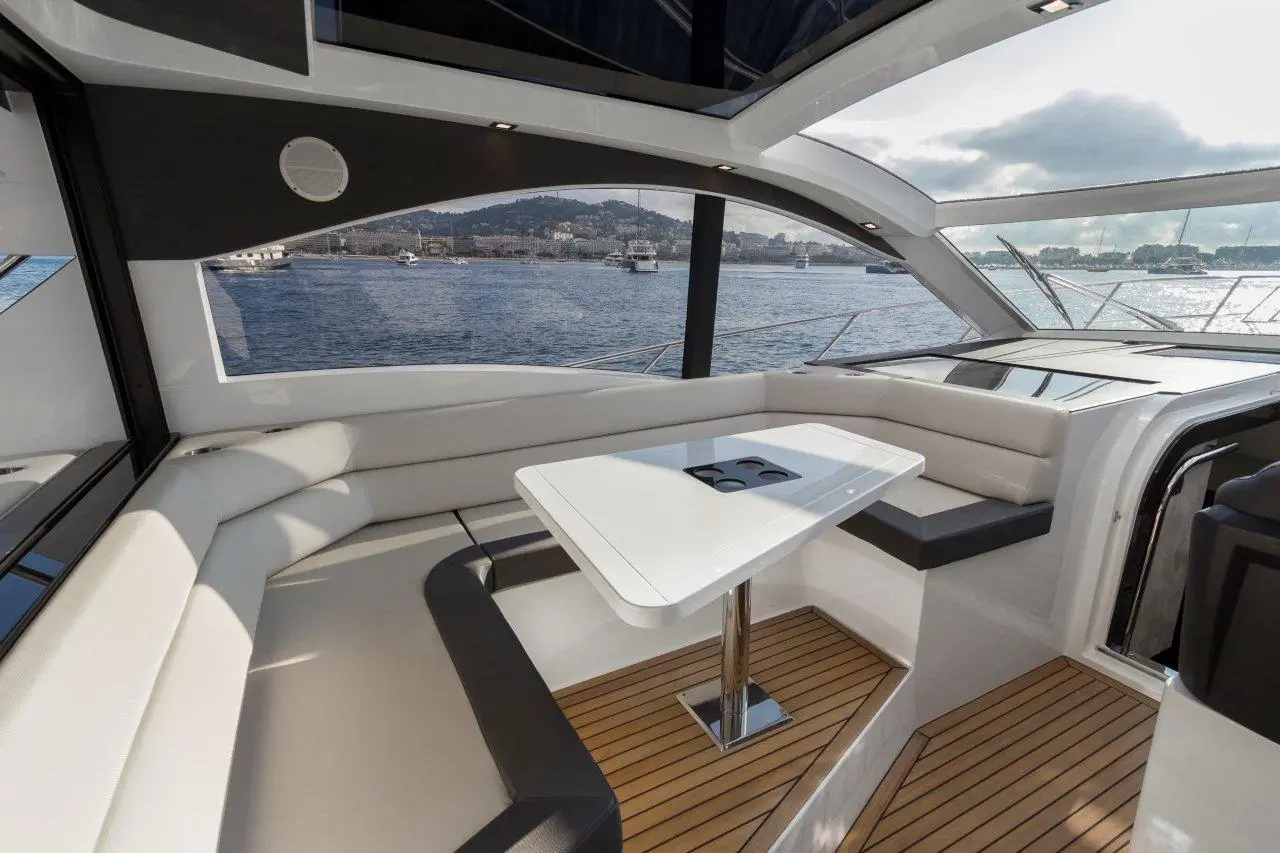 A modern yacht interior with a scenic view of the water, featuring a sleek table and comfortable seating area.