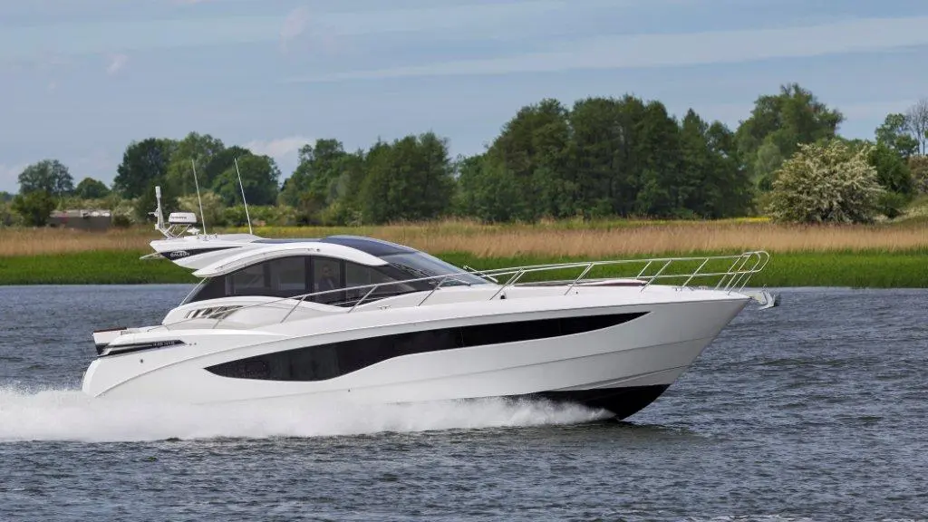 A sleek white motorboat cruising on calm waters, surrounded by green foliage and blue skies, highlighting summer leisure.
