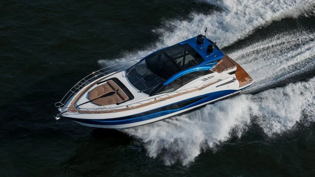 Luxury motorboat speeding on water, featuring a blue and white design with a spacious deck and visible wake from movement.