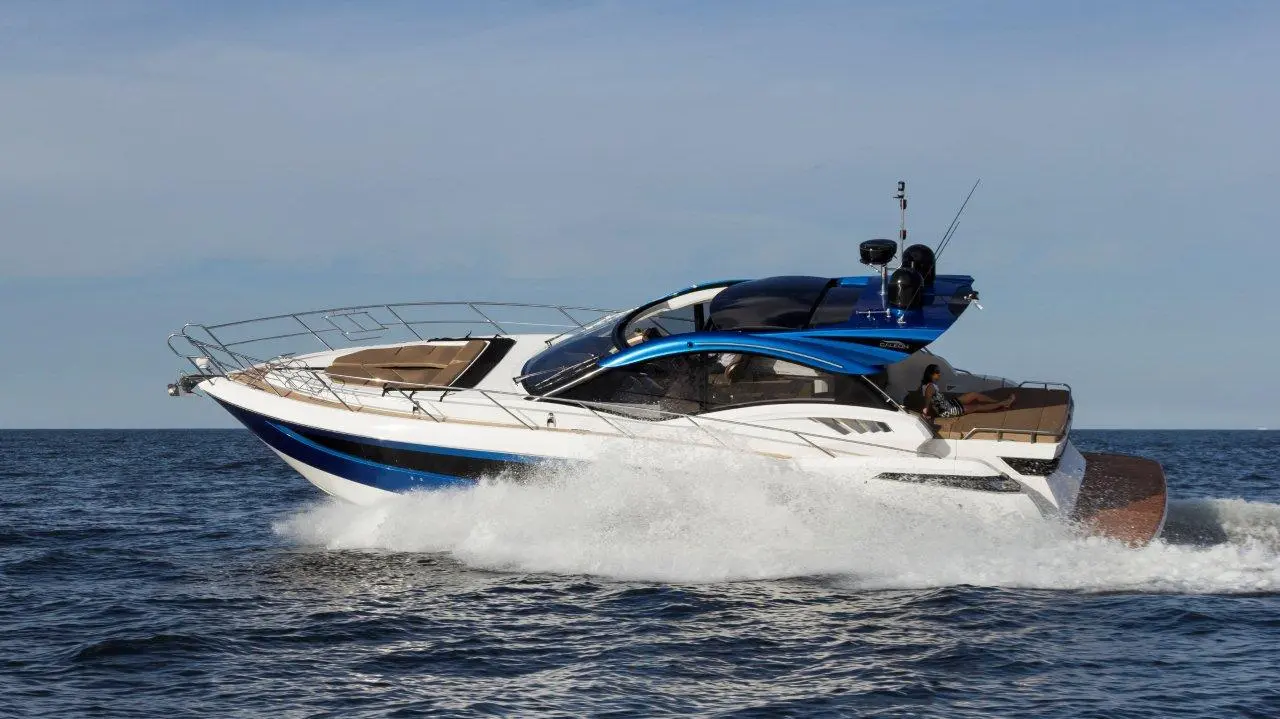 Luxury motorboat with sleek blue design cruising over waves on a sunny day, showcasing its spacious seating and modern features.