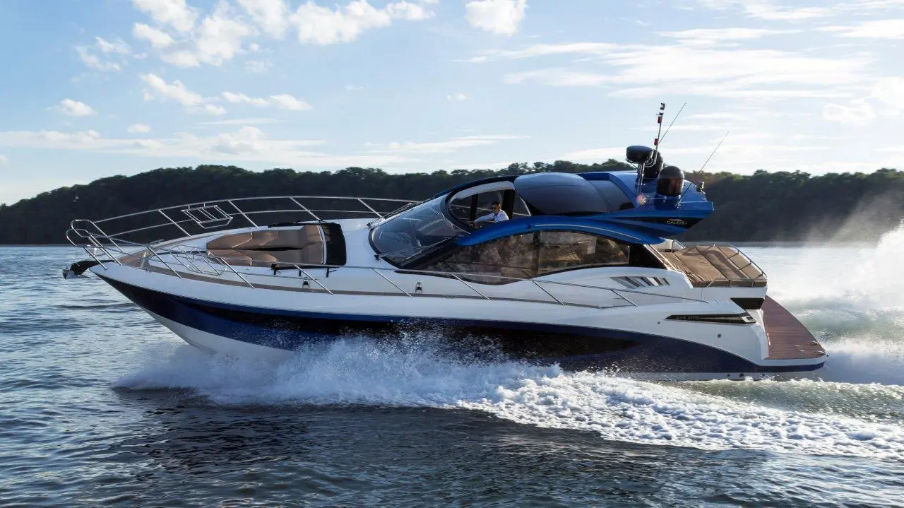 A sleek motor yacht cruises through water, leaving a wake; features a blue and white design with spacious seating and a radar.
