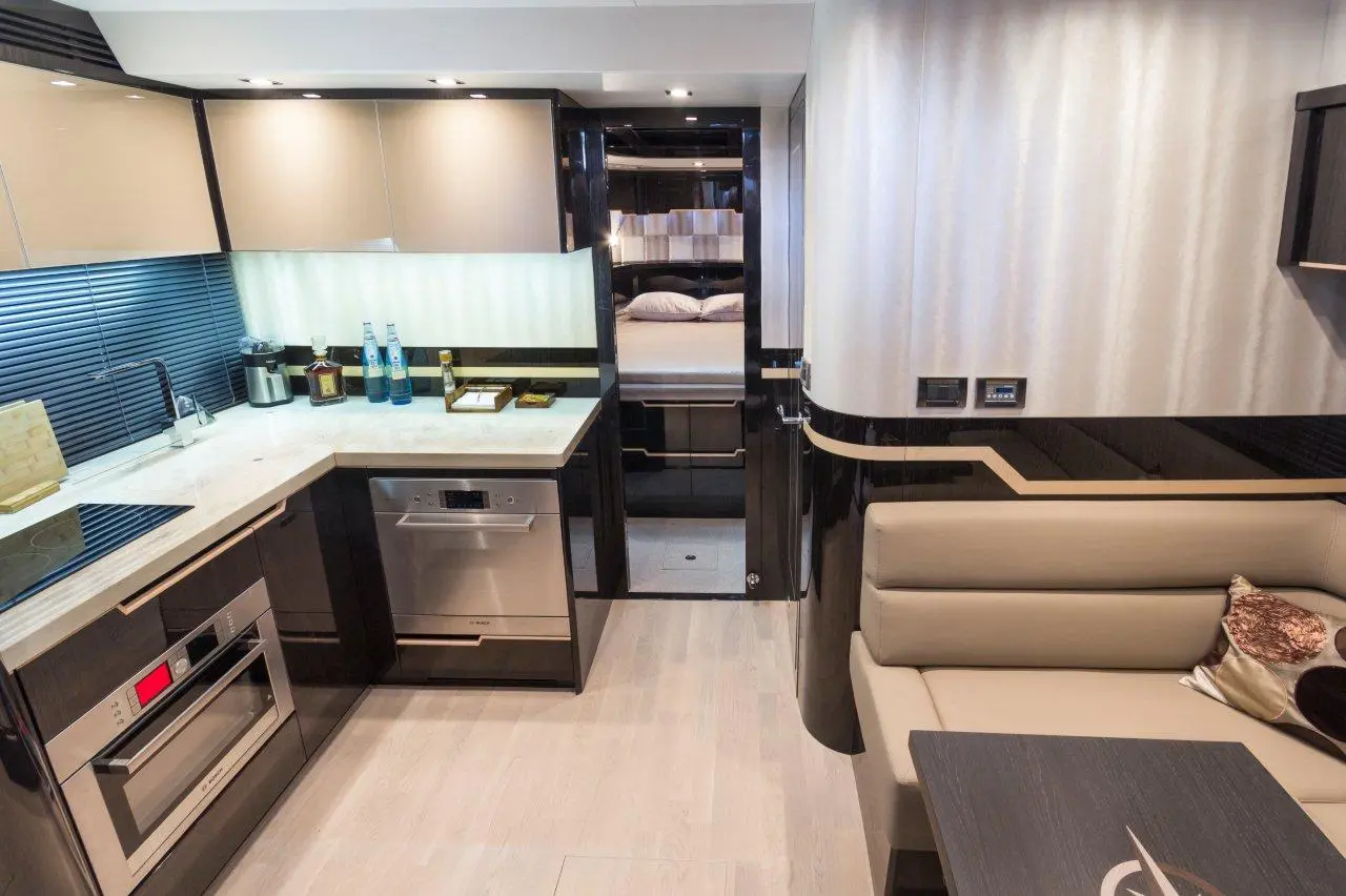 Modern kitchen with sleek cabinets, stainless appliances, a dining area, and a doorway leading to a bedroom in the background.