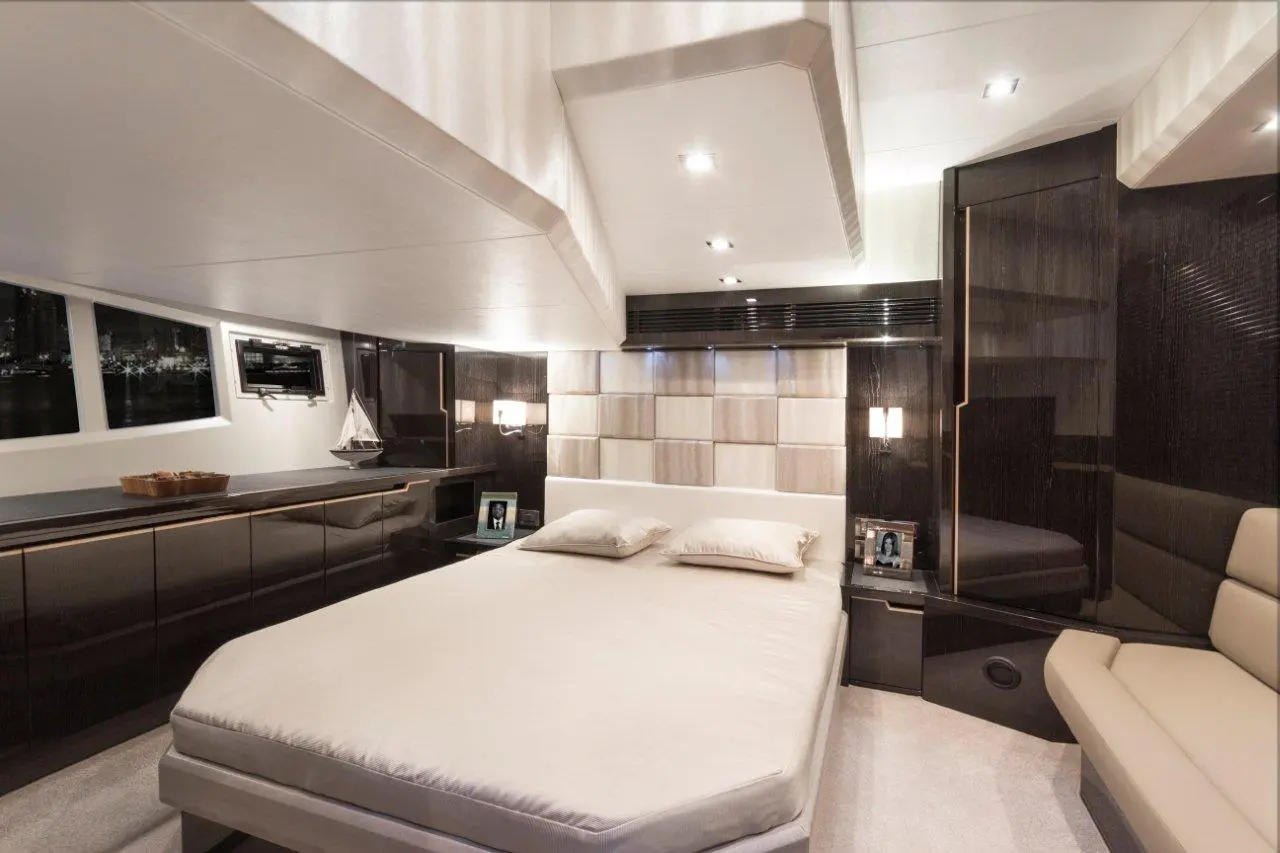 Luxury yacht interior featuring a sleek bedroom with a large bed, modern decor, and windows overlooking the water.