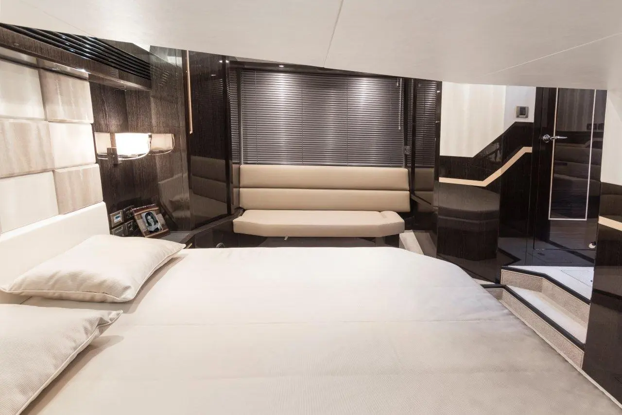 Luxurious modern yacht cabin featuring a queen bed, a sofa, and sleek decor with ambient lighting and window blinds.