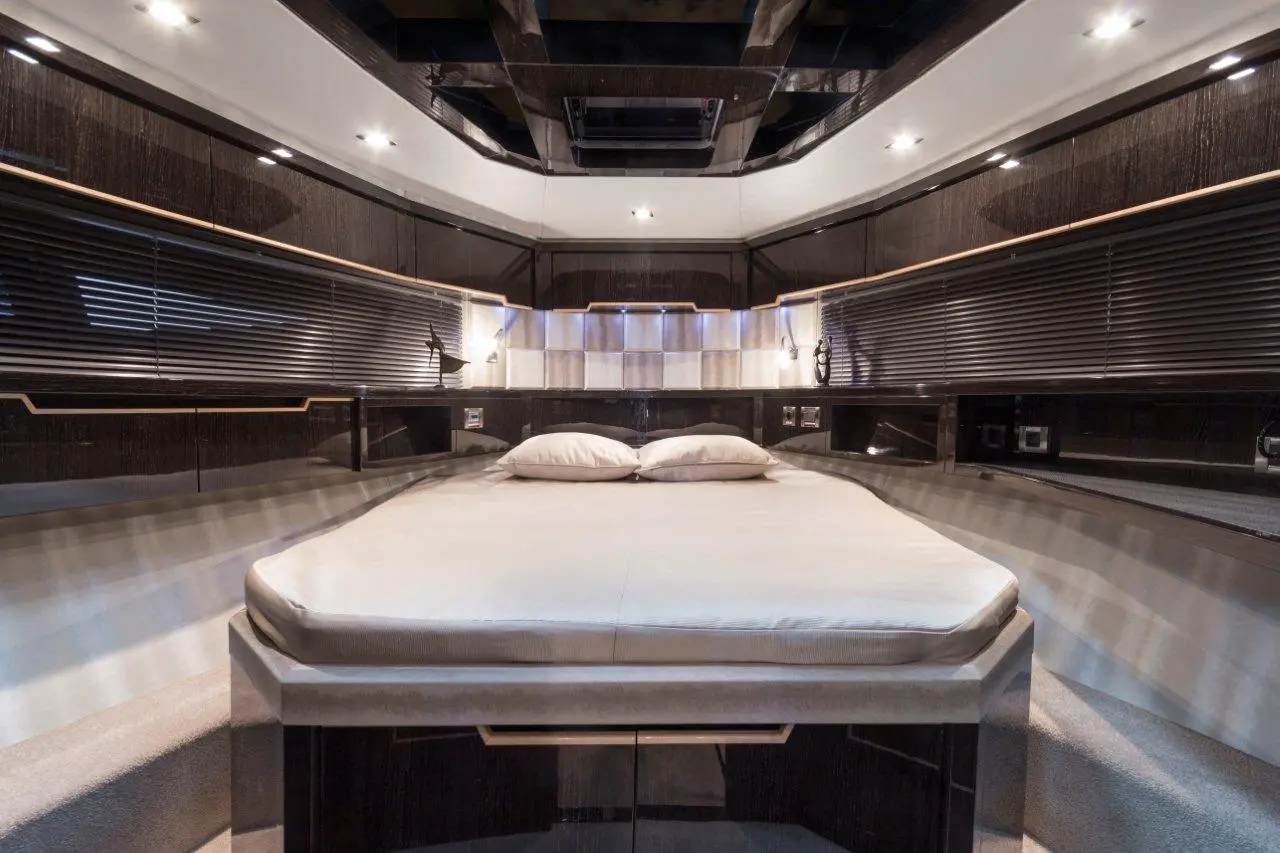 Luxury yacht interior featuring a stylish bedroom with a large bed, plush pillows, and sleek wooden finishes.