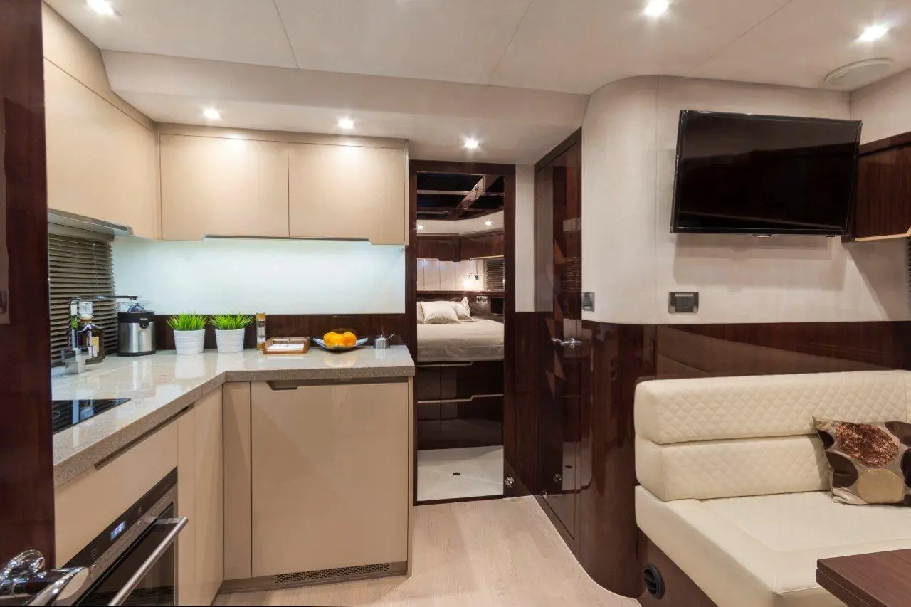 Modern yacht interior featuring a stylish kitchen with appliances, a dining area, and a bedroom entrance visible.