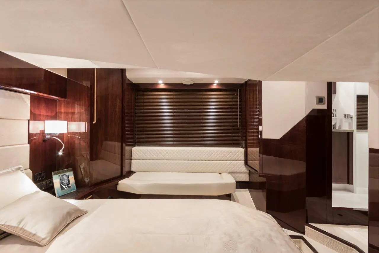Luxurious yacht interior featuring a cozy bedroom with a plush bed, seating area, and modern wooden accents.