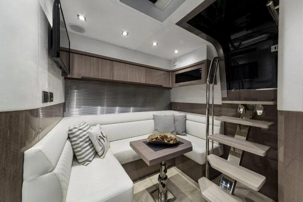 Elegant boat interior featuring a white seating area, wooden accents, a TV, and a stylish staircase leading up.