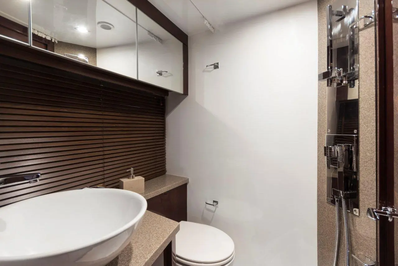 Modern bathroom with a white vessel sink, decorative wood blinds, shower controls, and neutral-toned surfaces.